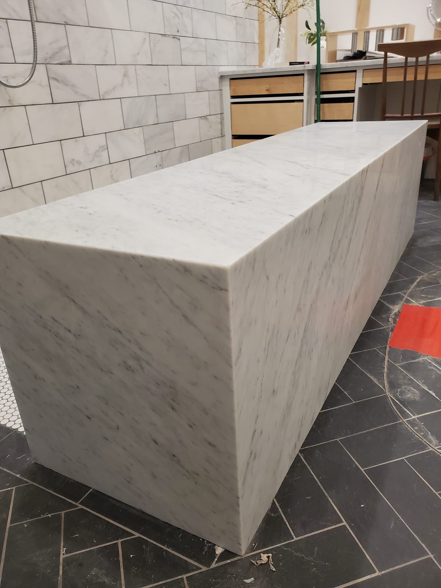 White marble rectangular bench, indoors. Light gray veining, angled sides.