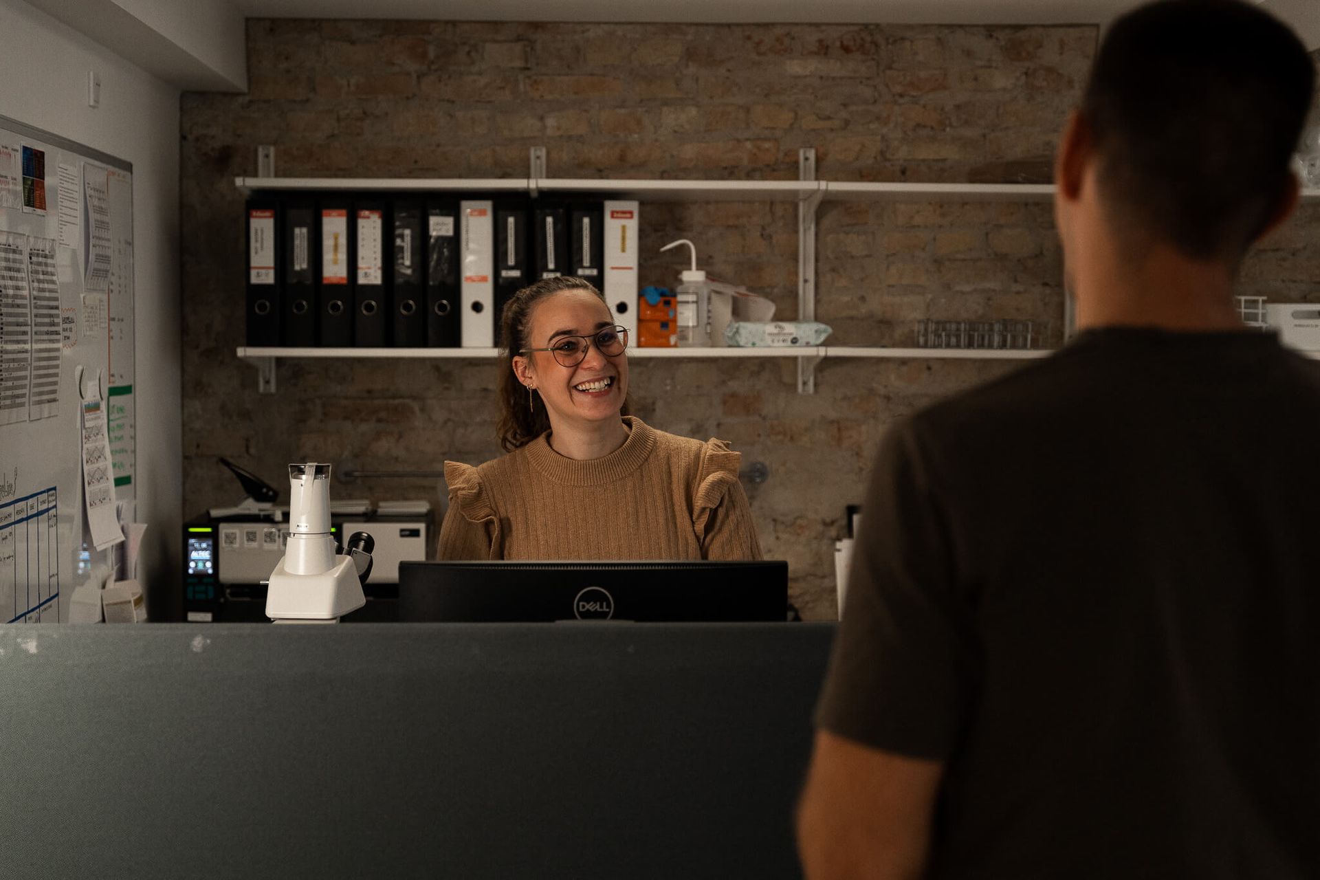 A man is standing in front of a woman behind a counter.