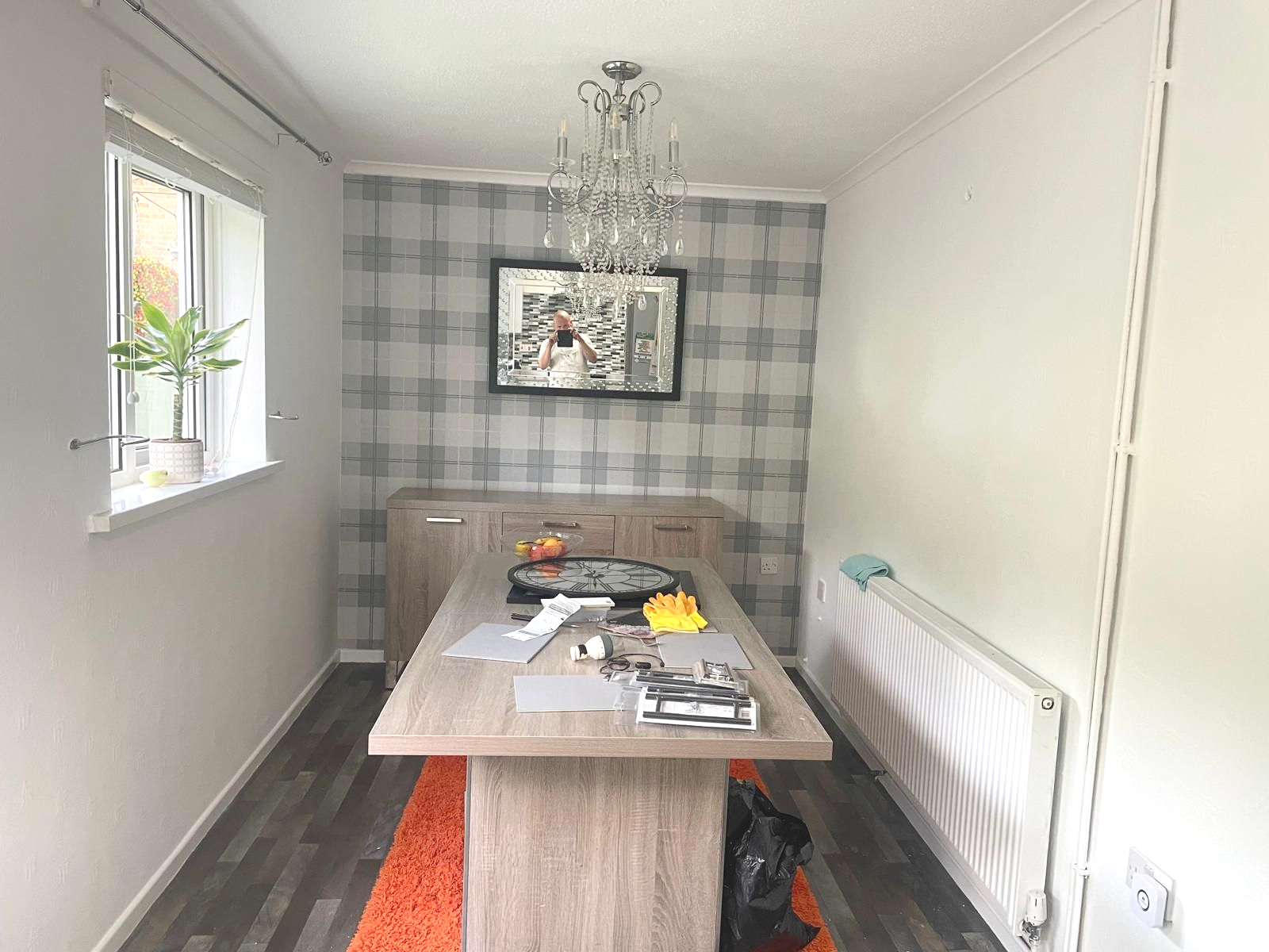 Dining room with a gray plaid accent wall, wooden table, and a chandelier.