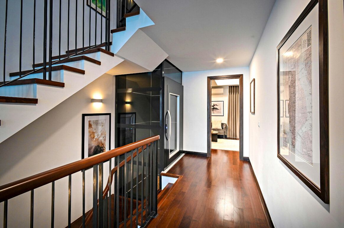 Hallway with dark wood floor, stairs, framed artwork, and a doorway.