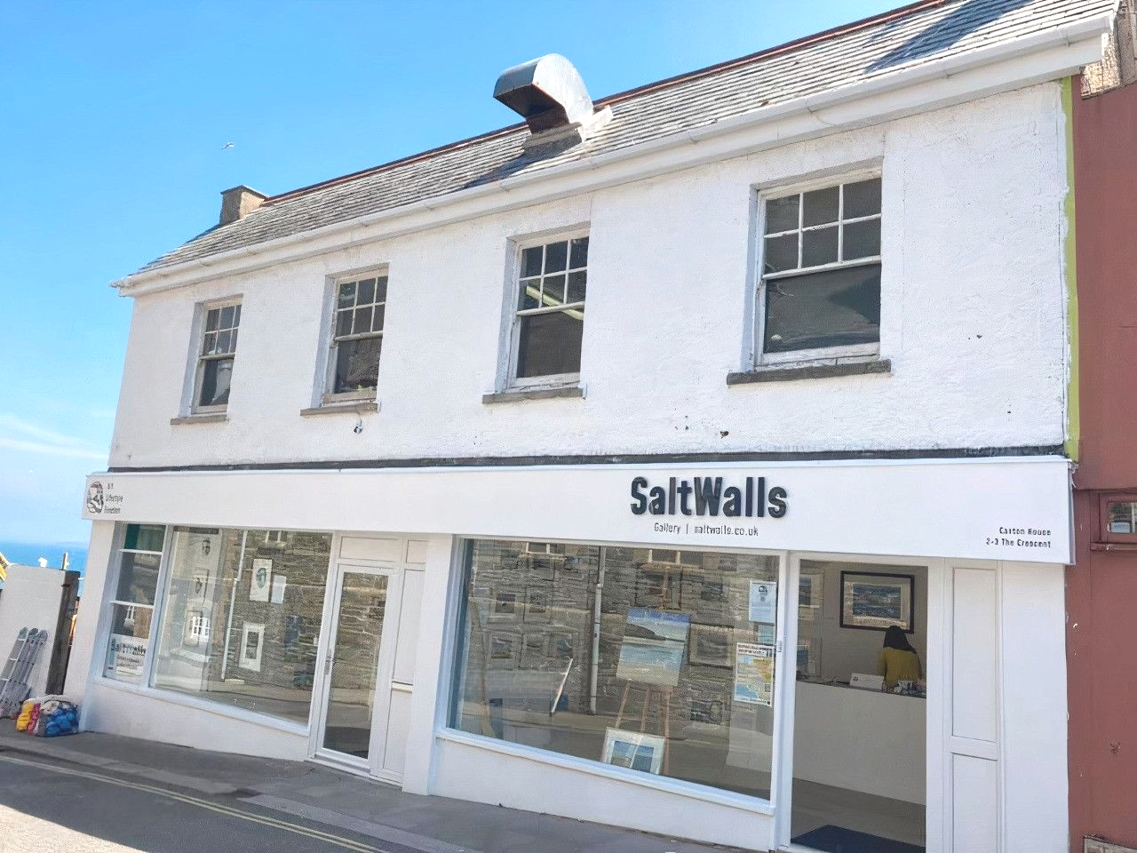 A white building with a sign that says saltwalls
