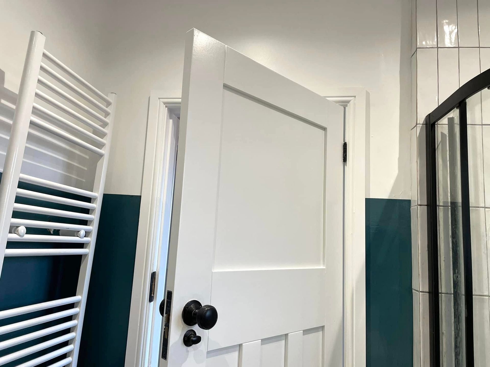 A bathroom with a white door and a towel rack.