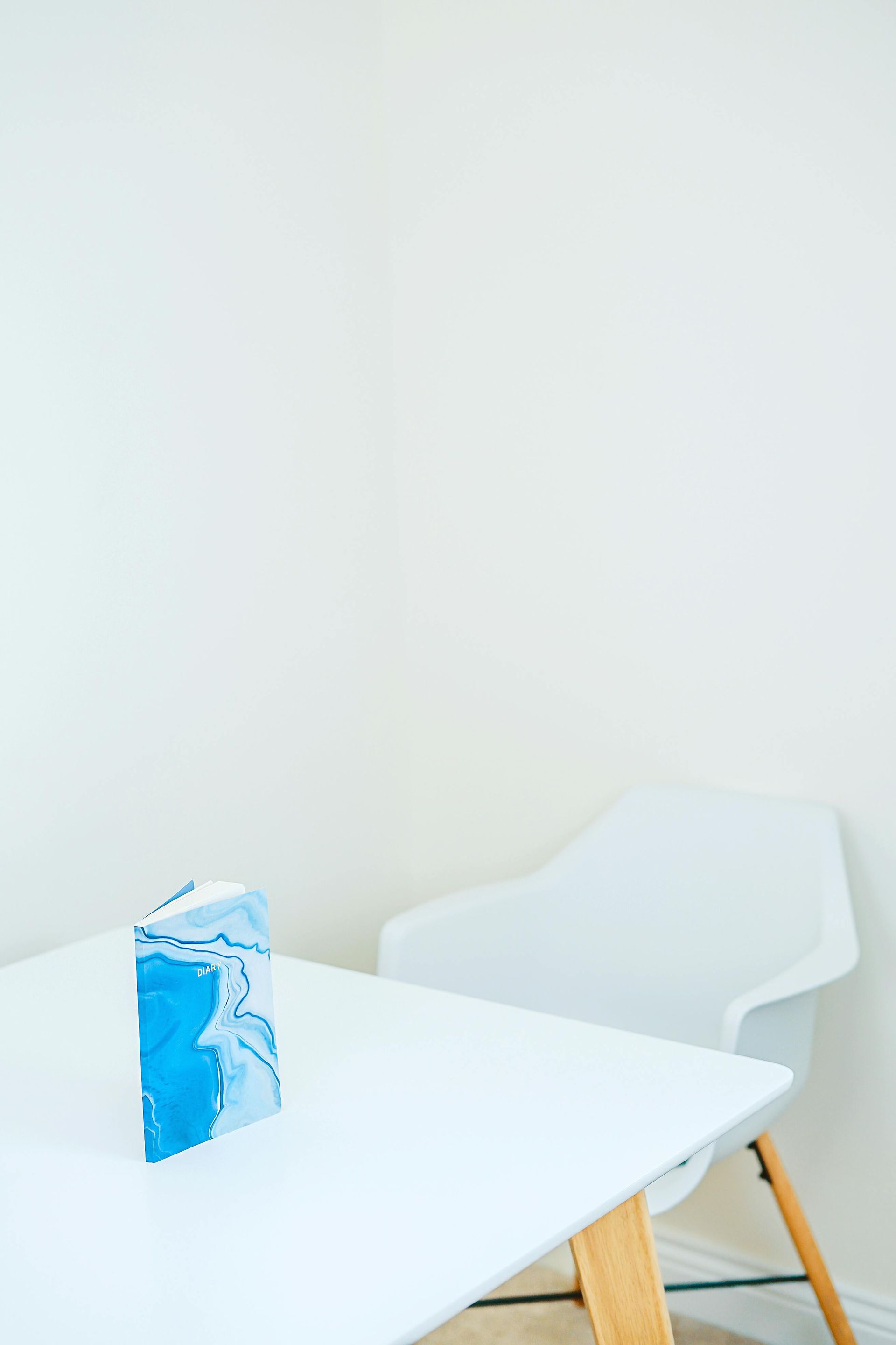 A book is sitting on a white table next to a chair.