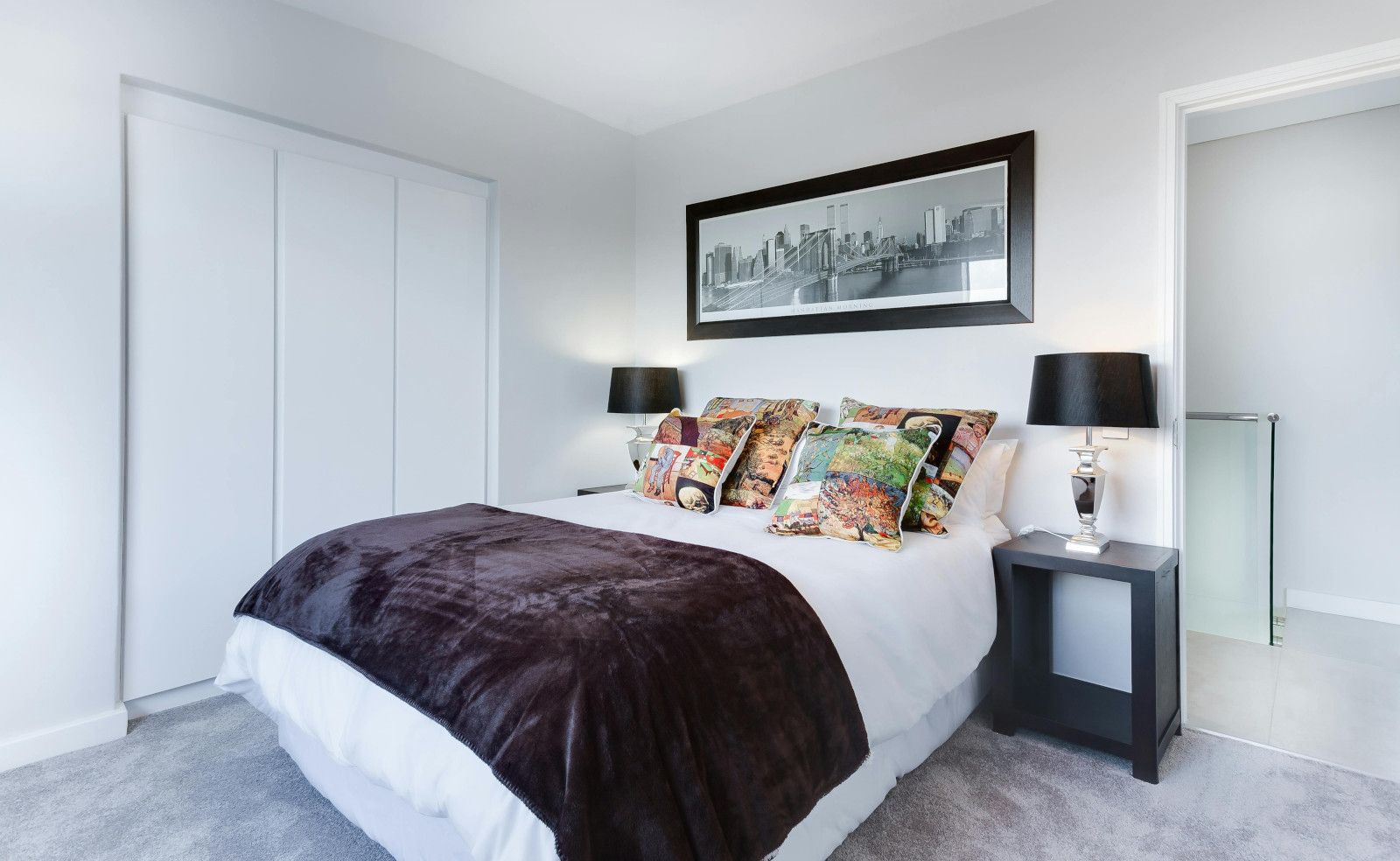 A bedroom with a large bed and a picture on the wall above it.