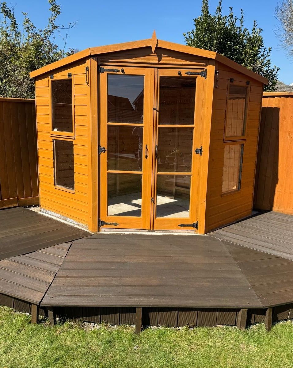 A wooden shed with a wooden deck in front of it