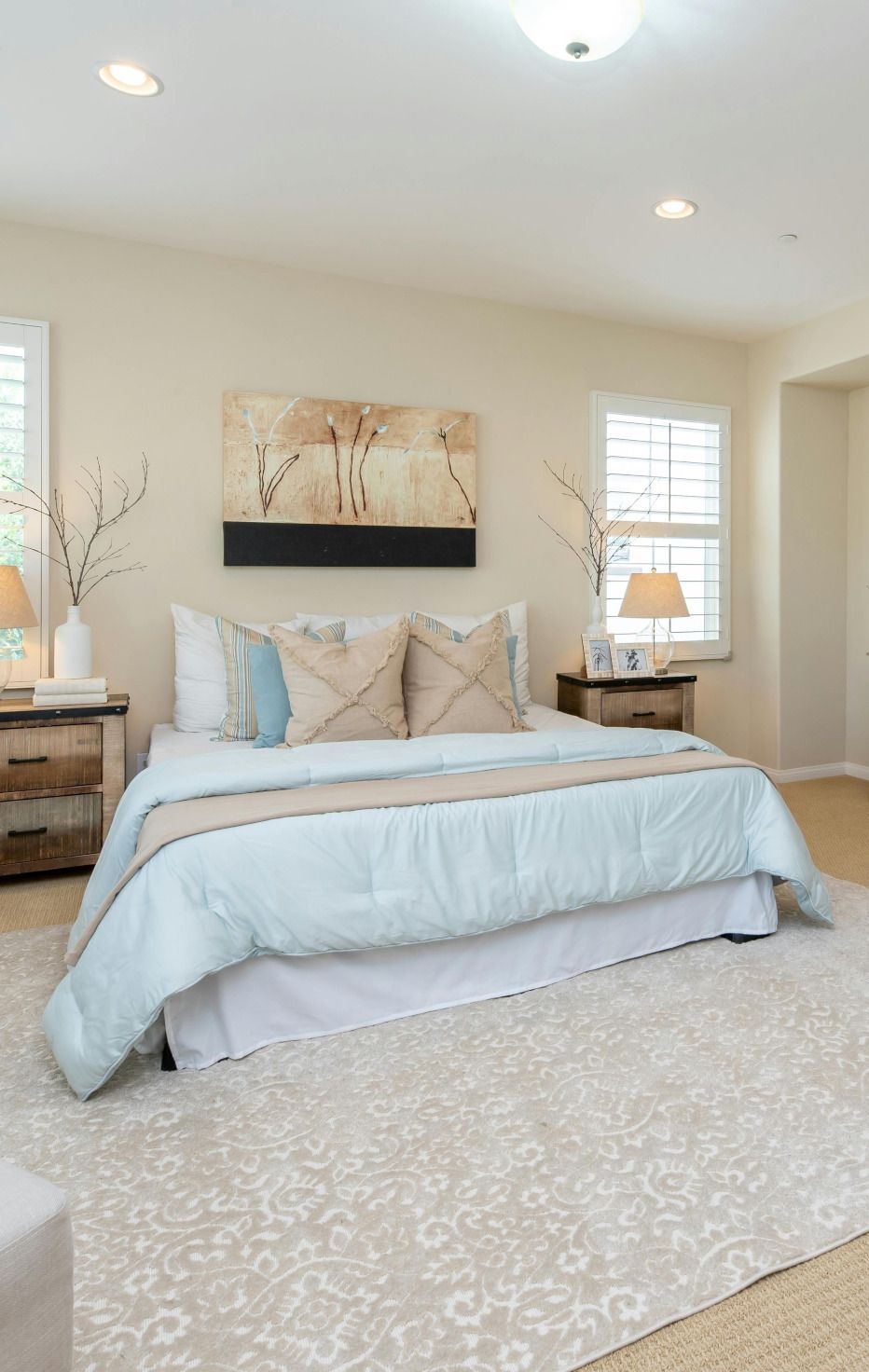 A bedroom with a bed , nightstands , a rug and a painting on the wall.