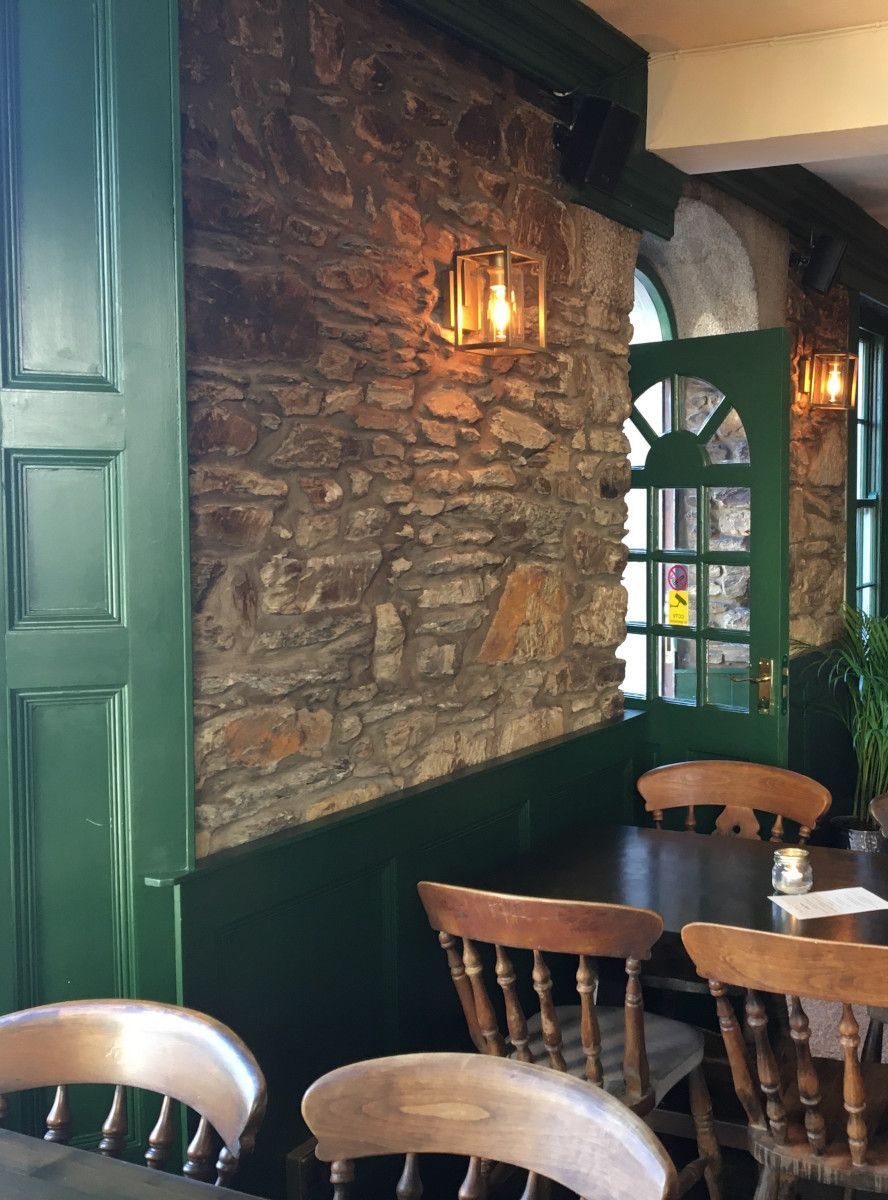 A restaurant with tables and chairs and a stone wall.