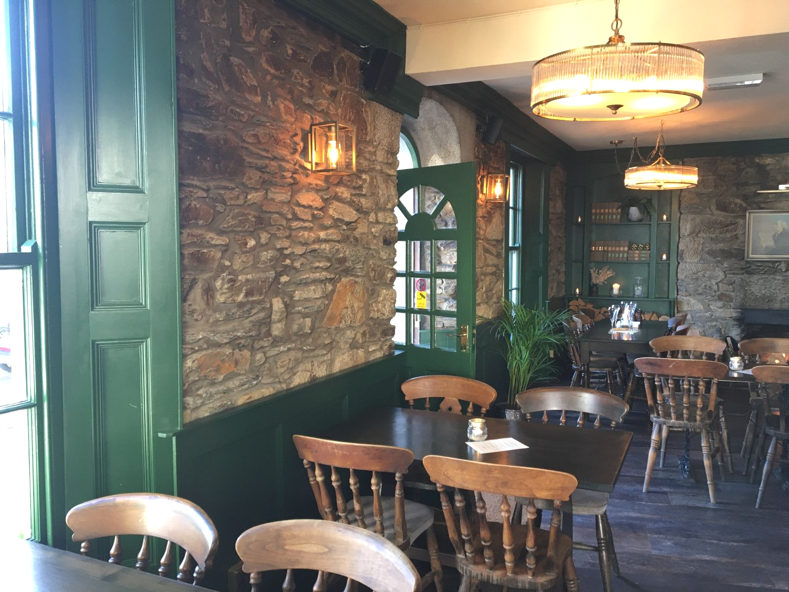 A restaurant with tables and chairs and a stone wall.