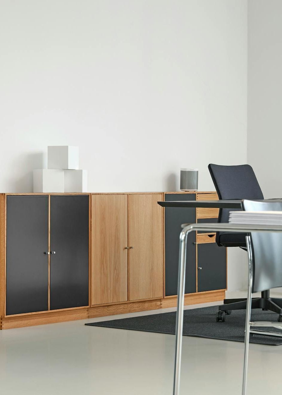 A modern office with a desk , chairs , cabinets and a laptop.