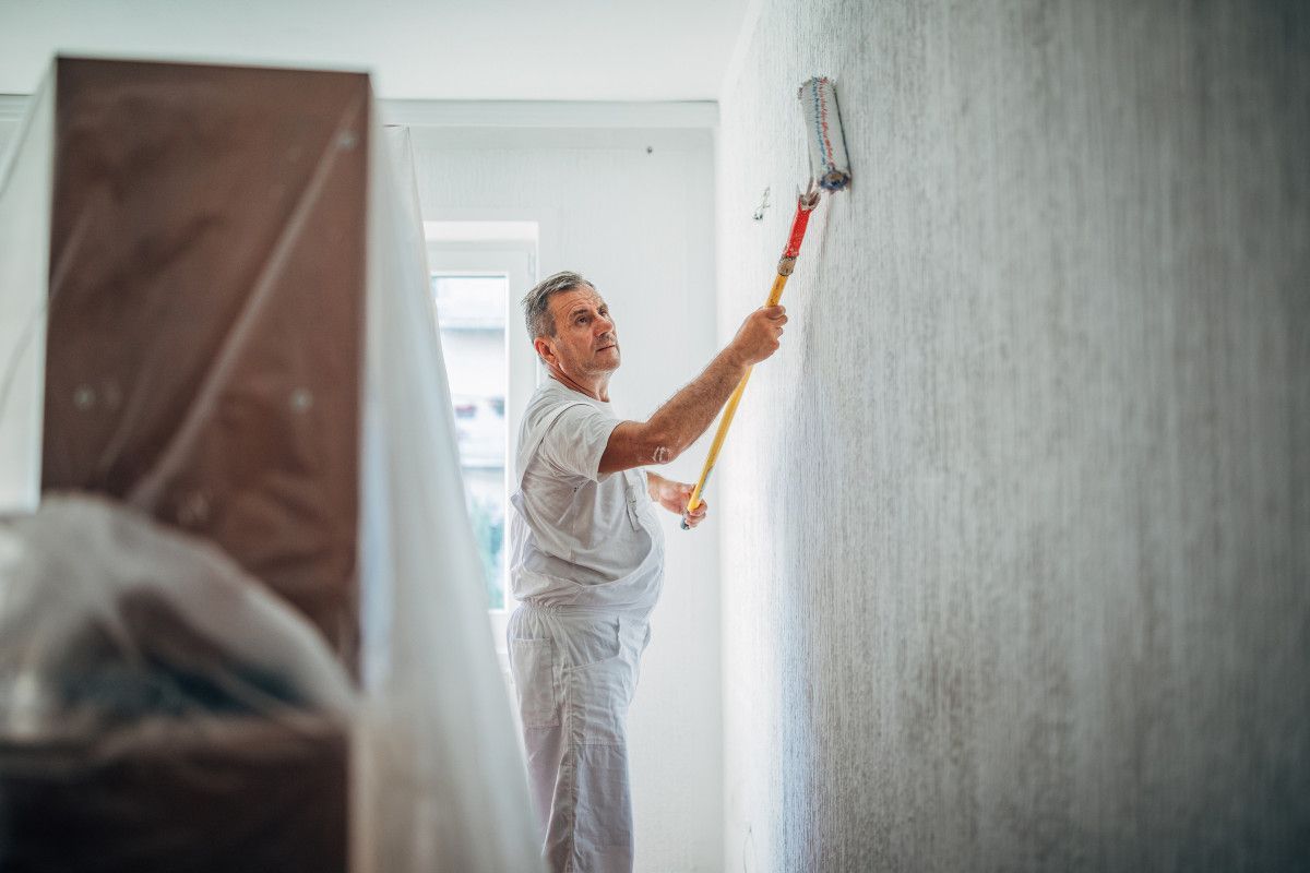 Daffodil Decor worker painting a wall with a paint roller in an interior room in Swansea.