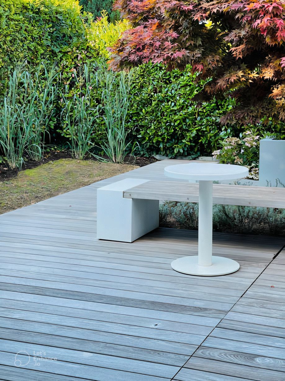 A table and bench are on a wooden deck in a garden.