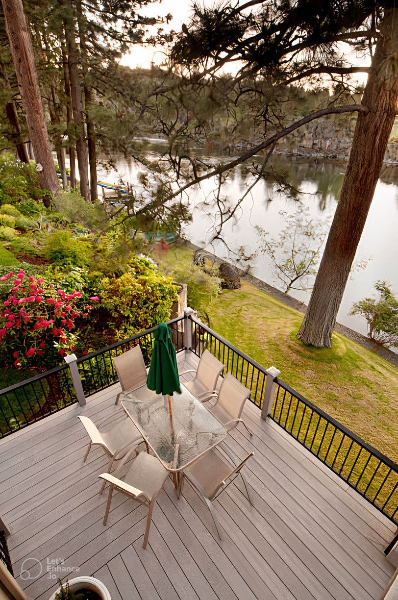 An aerial view of a deck with a table and chairs overlooking a lake.