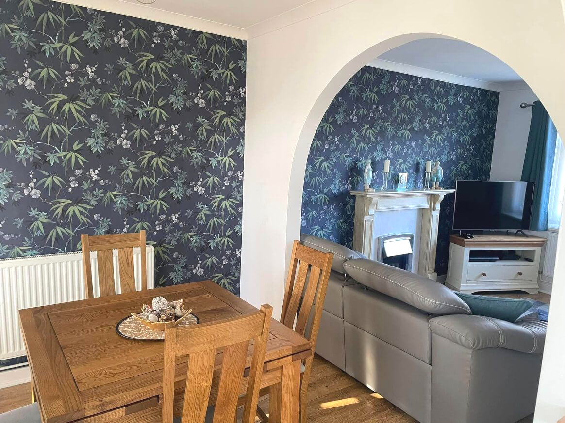 Dining room with table, chairs and floral wallpaper. Decorated by Daffodil Decor in Swansea.