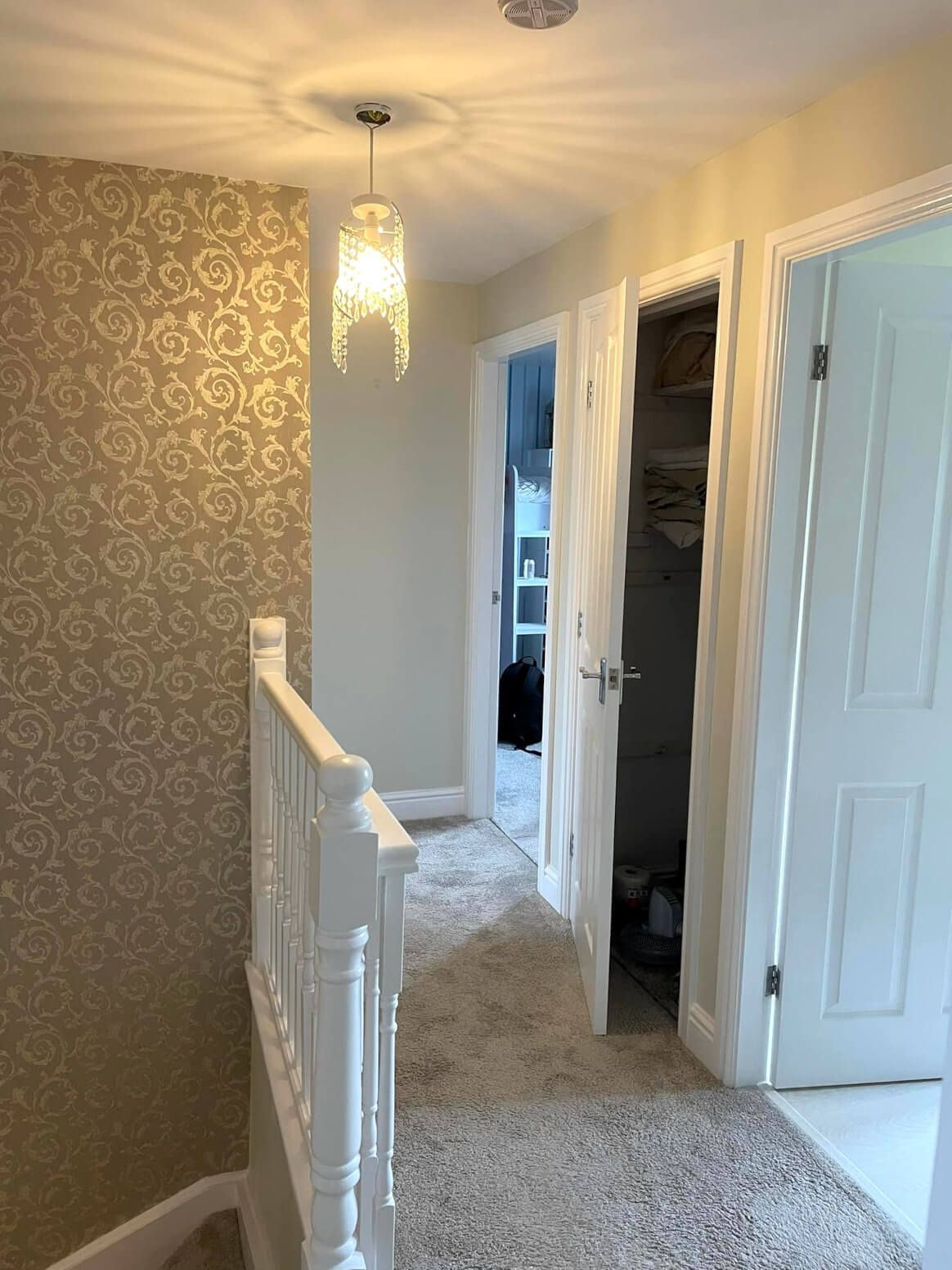 Upstairs hallway and landing inside newly decorated Swansea home. Wallpaper, painted walls, wood trim, and door frames by Daffodil Decor.