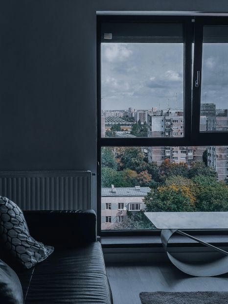 A living room with a couch and a window with a view of a city.