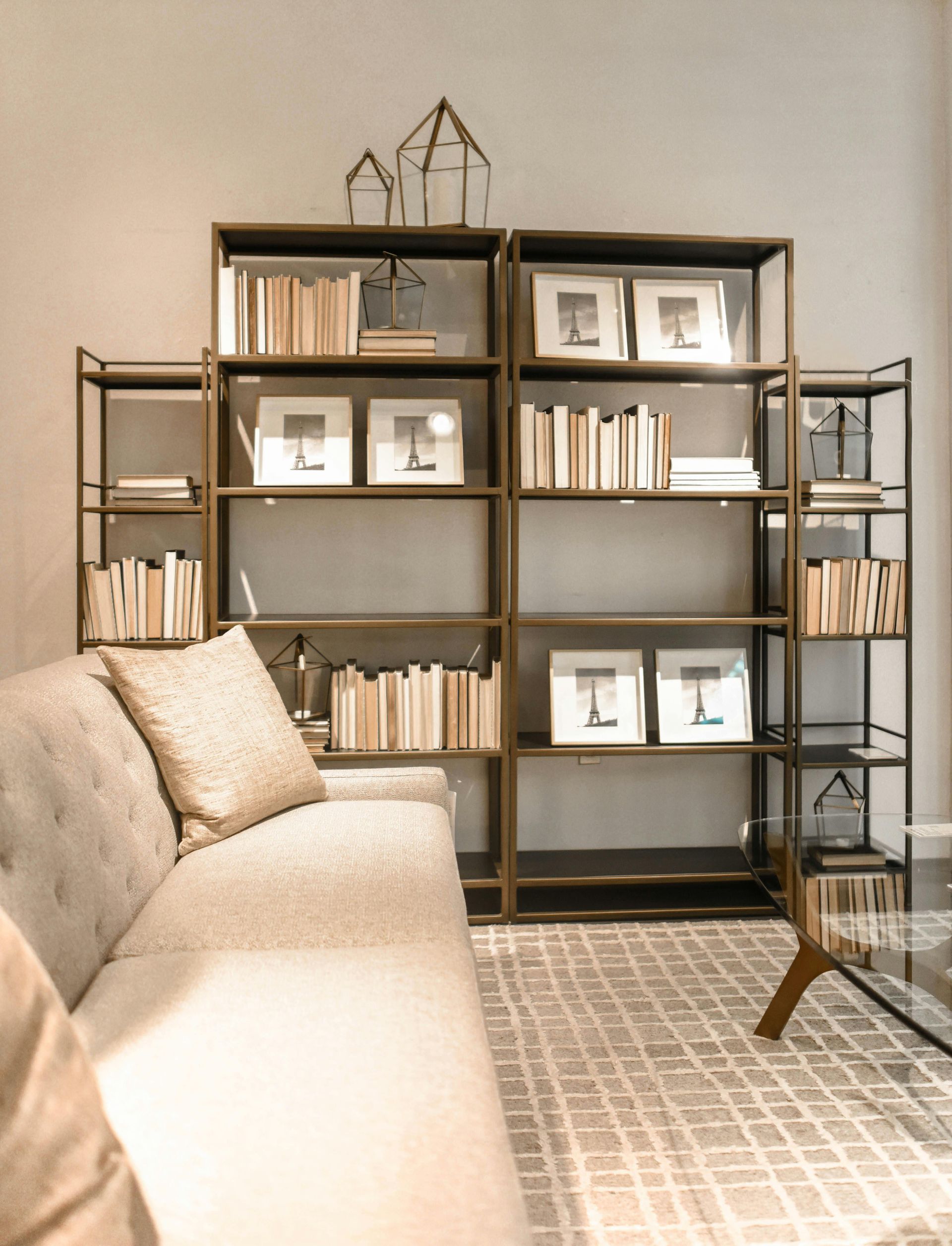 A spacious living room area with bookcase, sofa and tile floor.