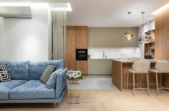 A living room with a blue couch and a kitchen in the background.