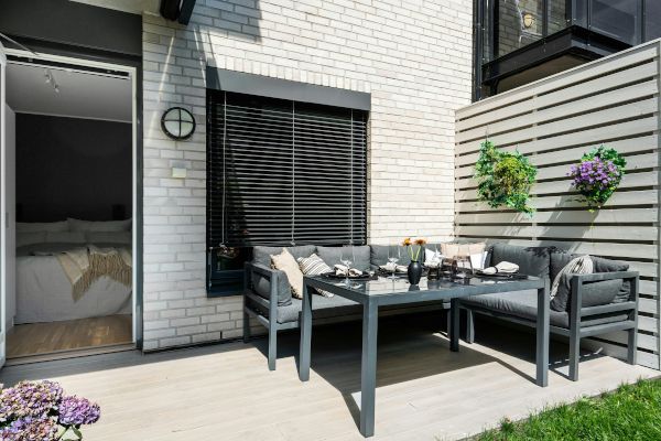 A patio with a table and chairs in front of a brick building.