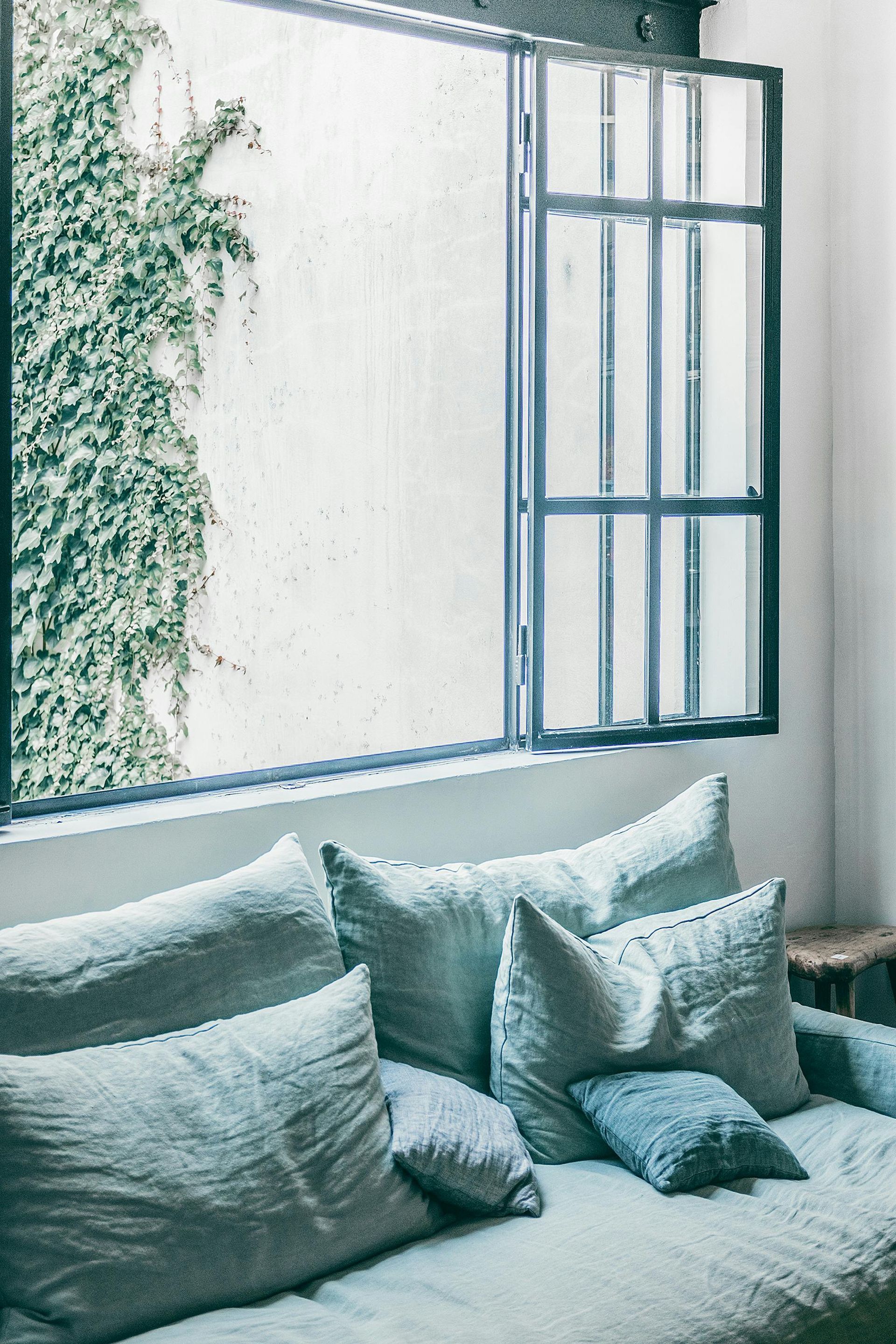 A home living room with expansive open window and white & light blue wallpaper. Expertly decorated by Daffodil Decor in Swansea, Wales.