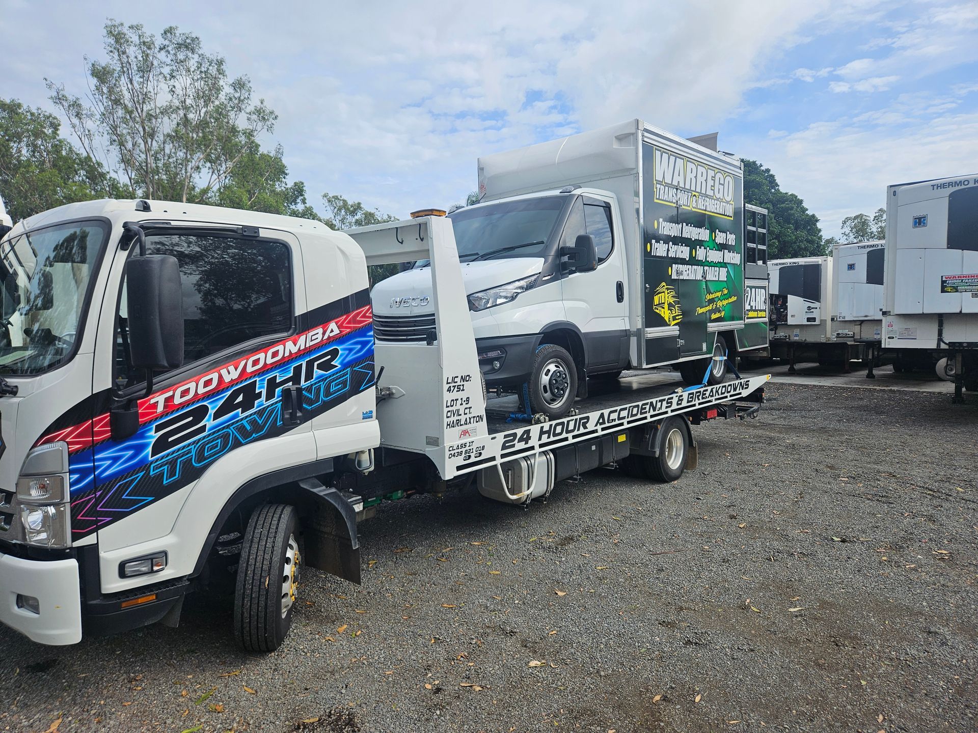A white tow truck carries a white box truck on a gravel lot under a bright, cloudy sky. — JP's Towing and Transport in Toowoomba City, QLD