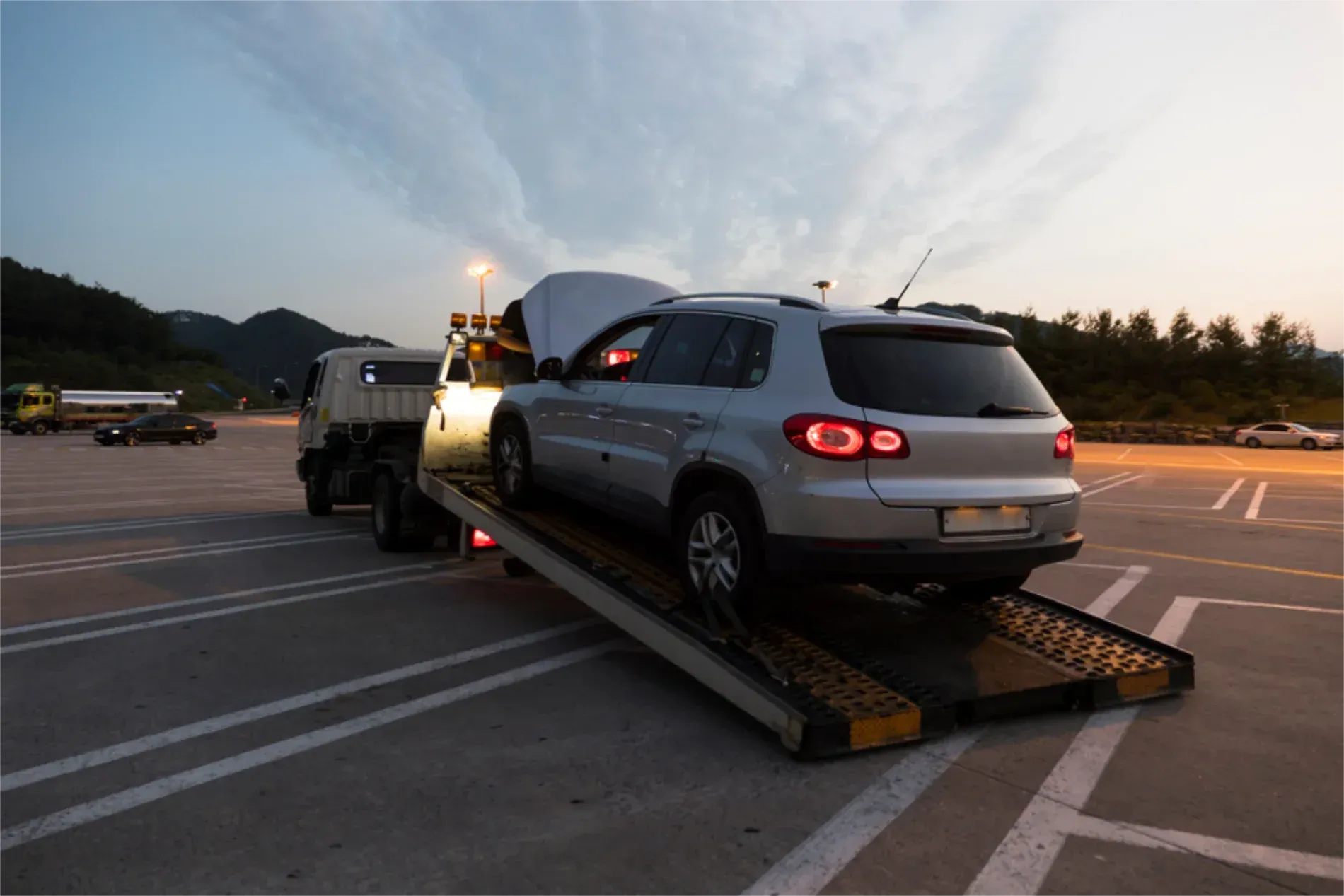 A Silver Suv With Its Hood Open is Being Loaded Onto a Flatbed Tow Truck — JP's Towing and Transport in Esk, QLD