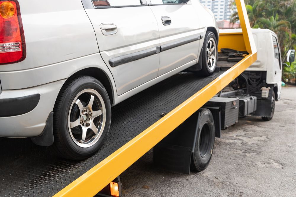 A Silver Car Parked on the Slanted Flatbed of a Yellow Tow Truck — JP's Towing and Transport in Westbrook, QLD