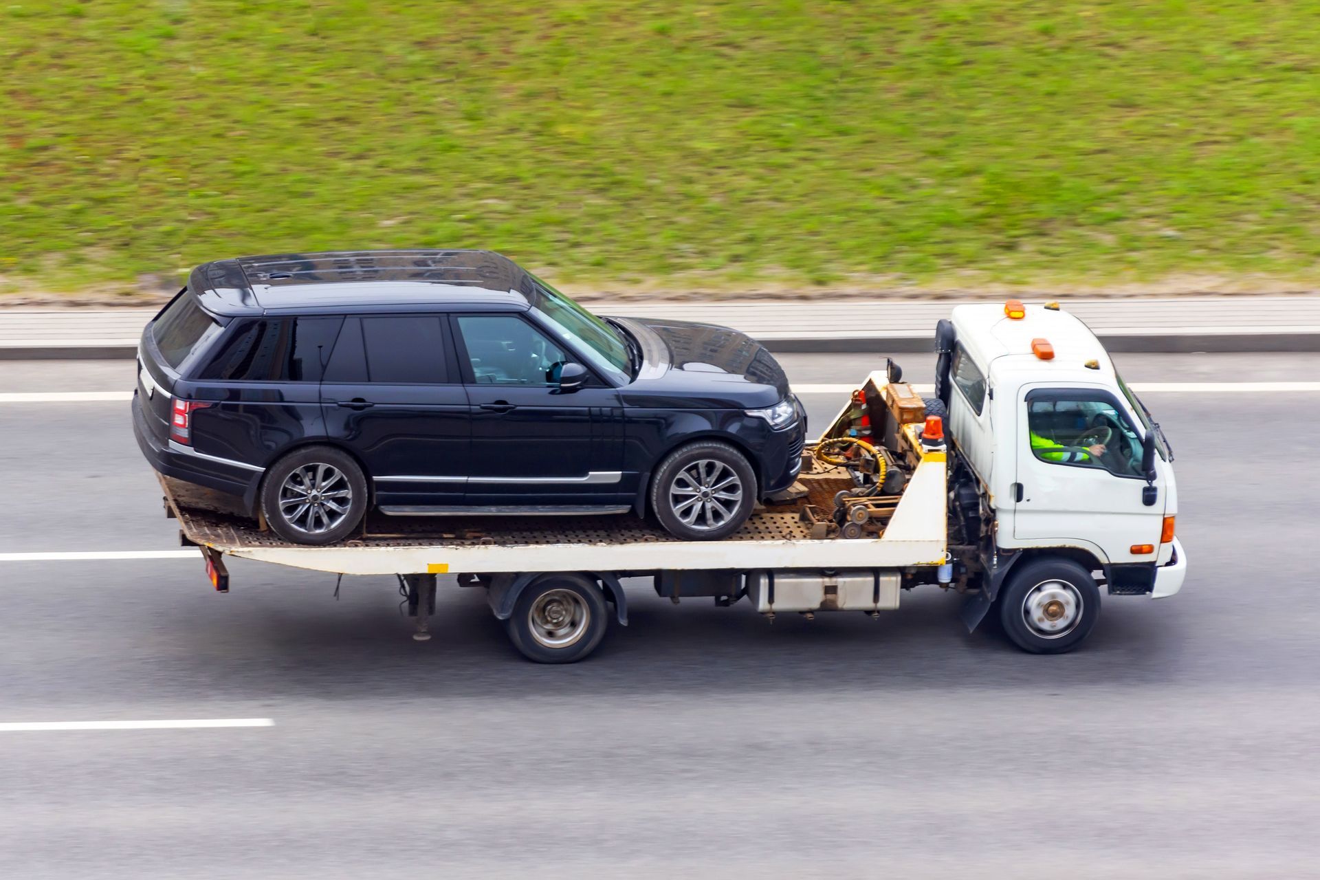 A Flatbed Tow Truck Transporting a Black Range Rover on a Highway — JP's Towing and Transport in Toowoomba City, QLD