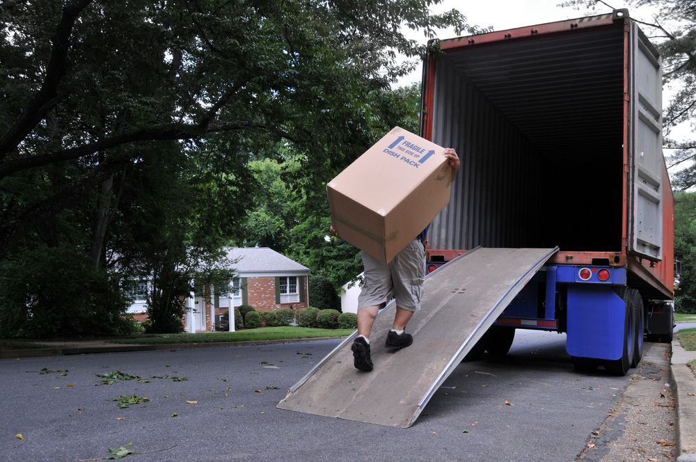A Person Carries a Box Up Into the Back of a Parked Shipping Container — JP's Towing and Transport in Gatton, QLD