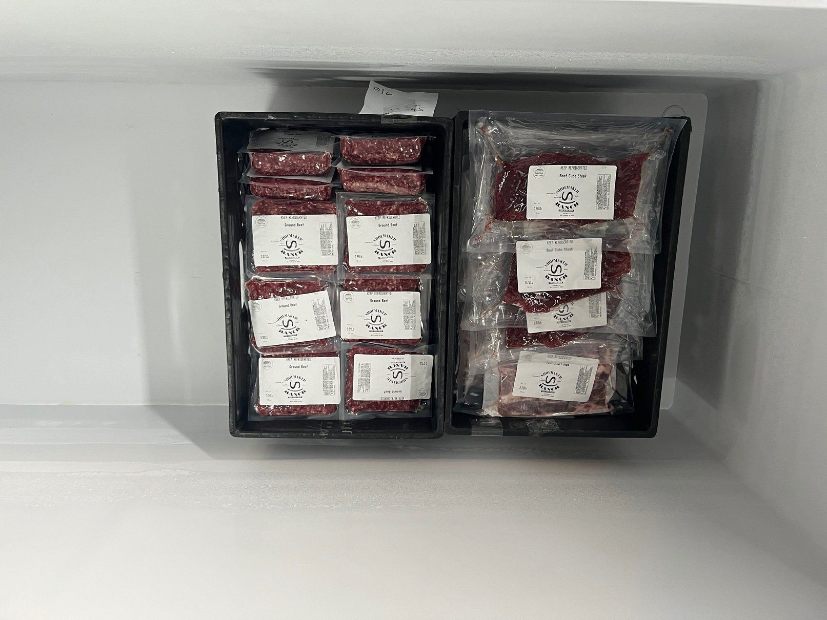 Two boxes of meat are sitting in a freezer.