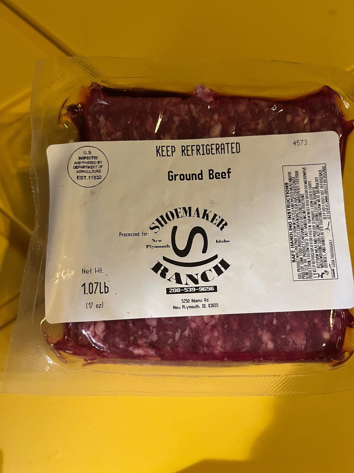 A package of ground beef is sitting on a yellow table