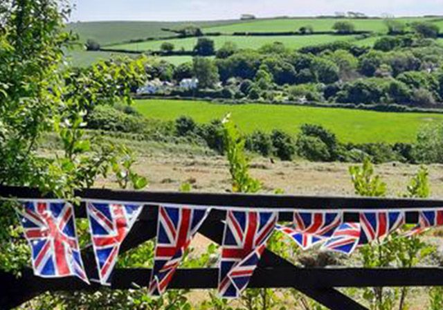 Union Jack bunting with a scenic rural background of green fields and hills.