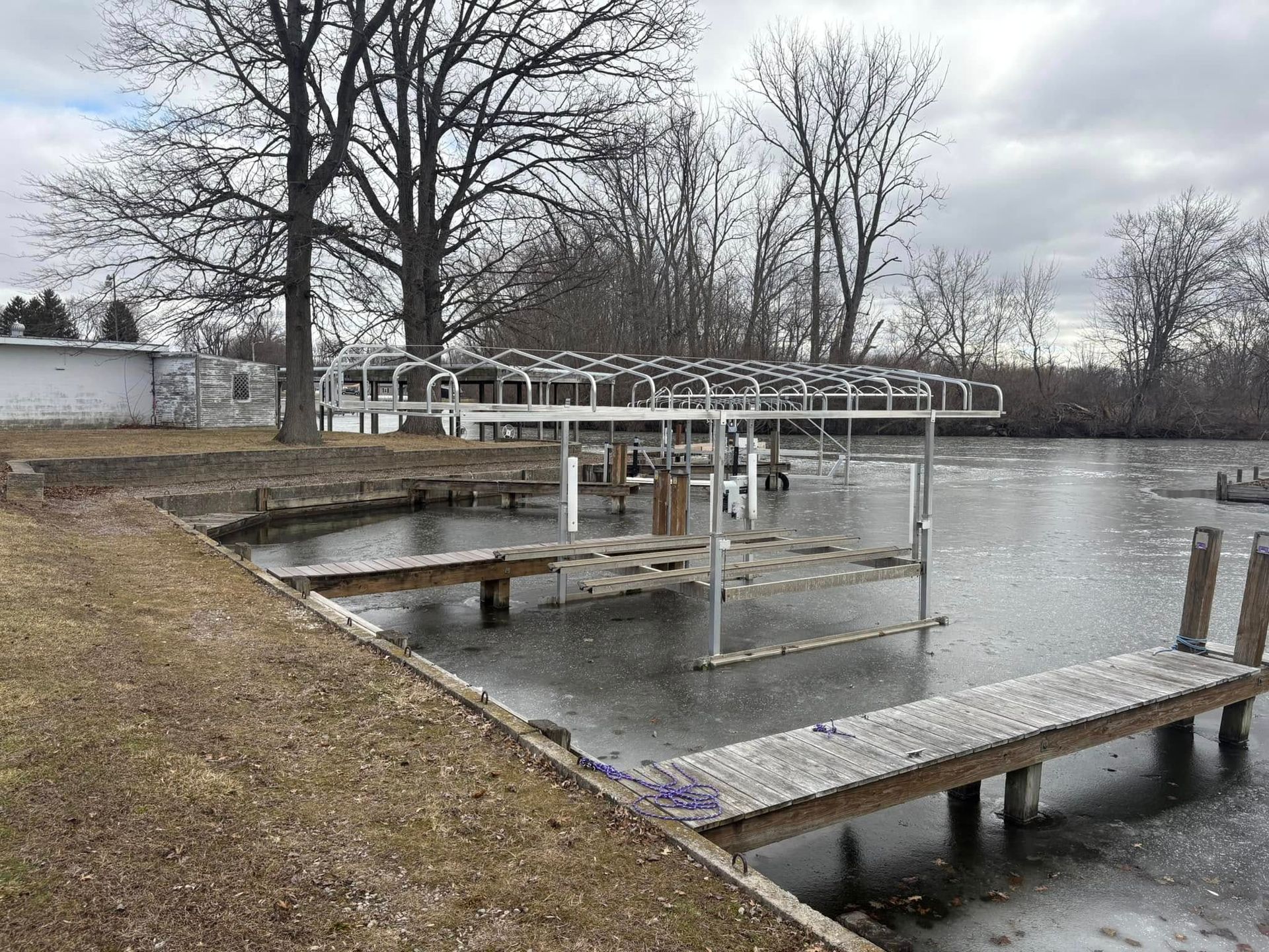 Docks extending into a calm lake beside bare trees under a cloudy sky