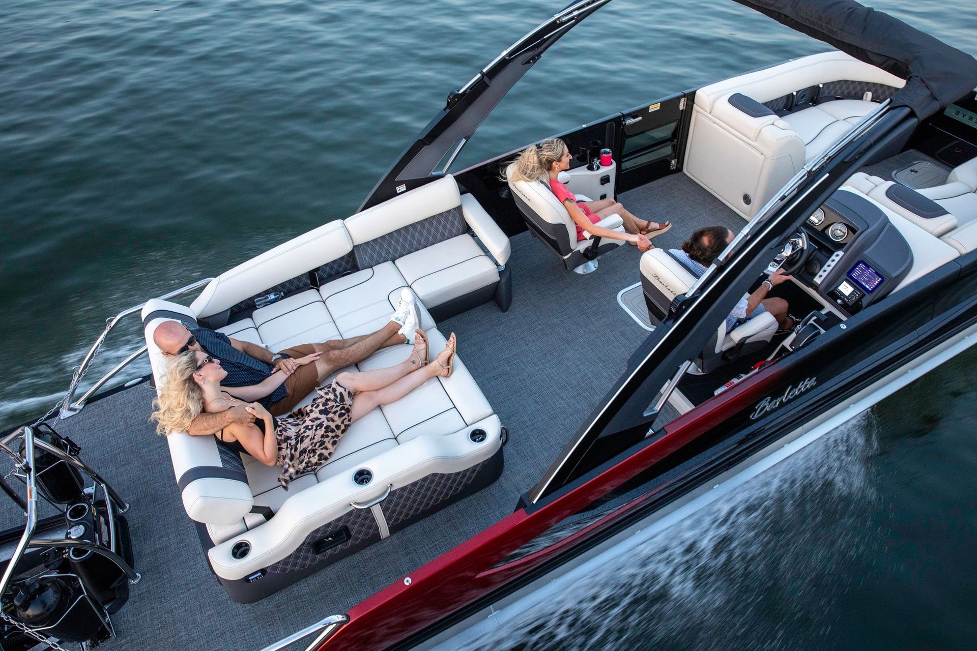 People lounging on a sleek motorboat with white seats on open water