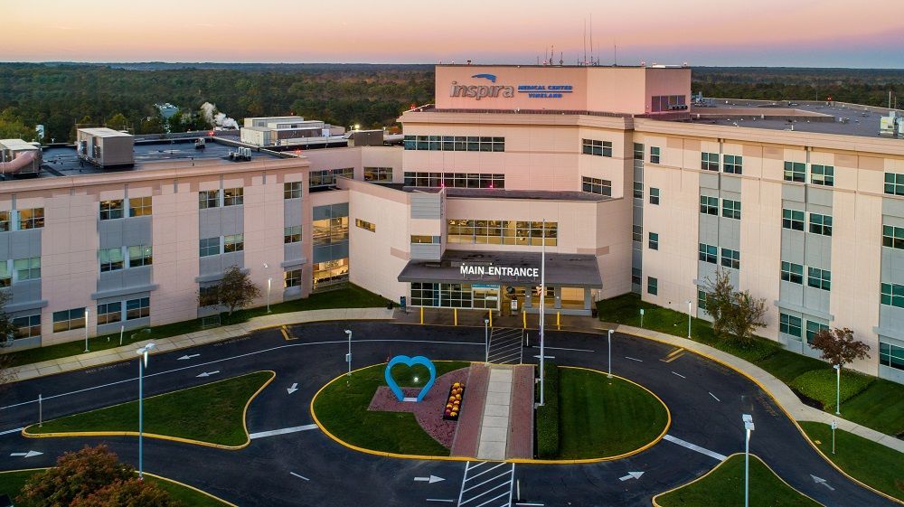 Hospital building entrance with circular driveway and landscaped center at dusk