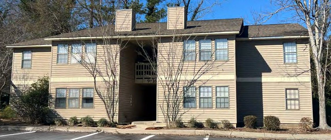 A large apartment building with a lot of windows and trees in the background.