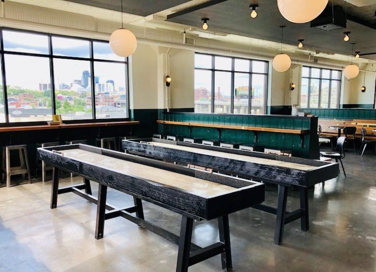 A large room with a shuffleboard table in the middle of it.