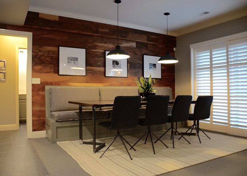 A dining room with a table and chairs and a wooden wall.