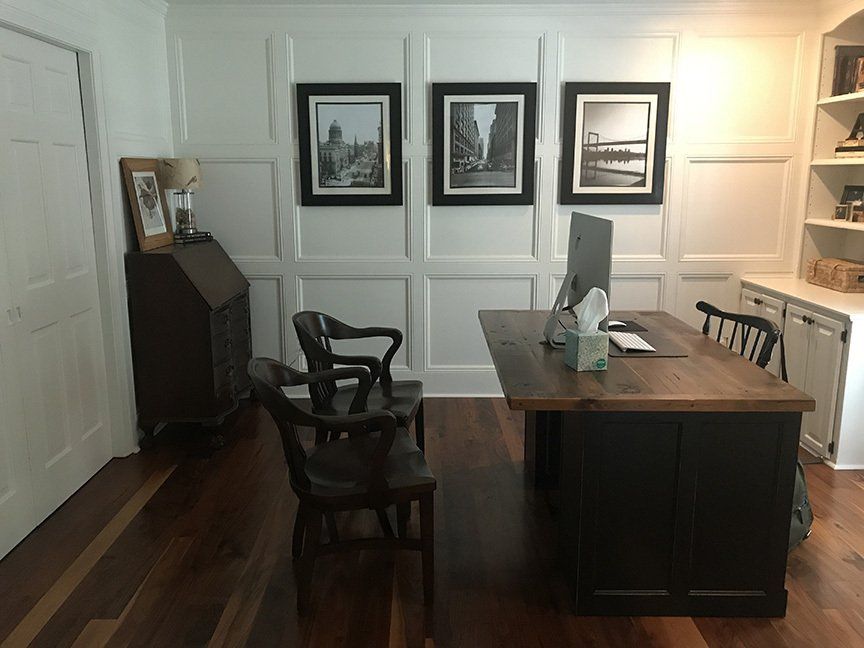A home office with a desk , chairs and pictures on the wall