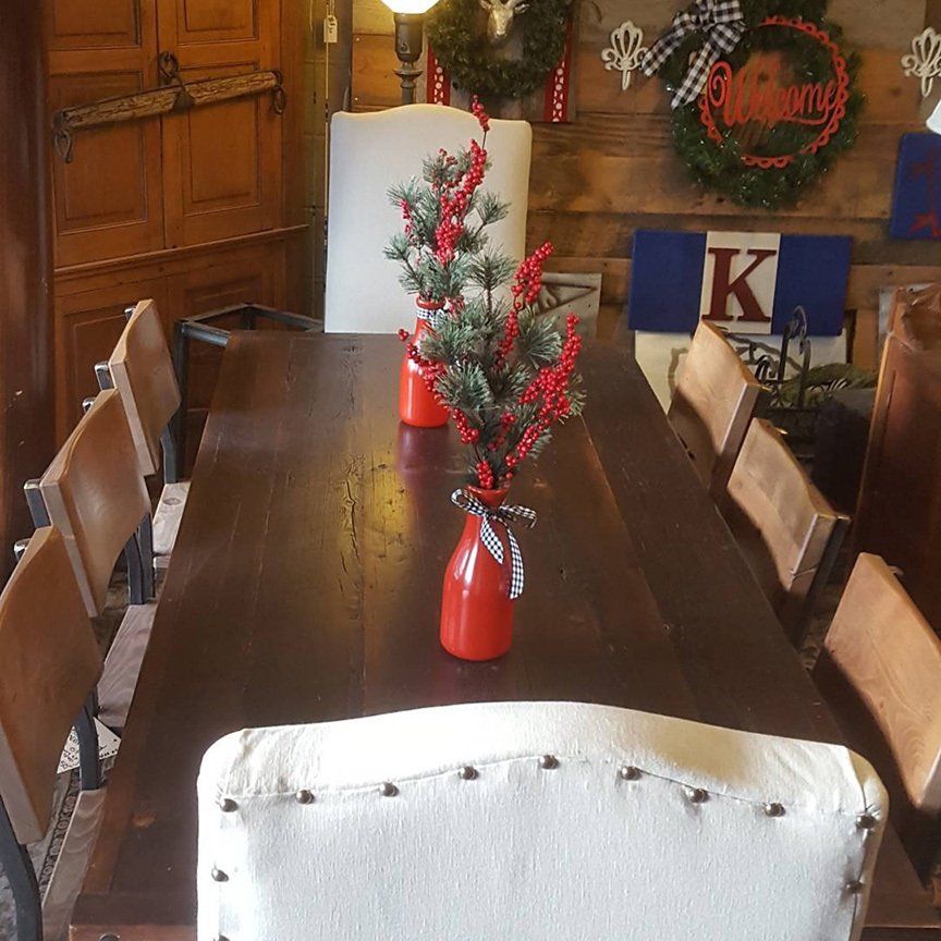 A dining room table with a vase of christmas decorations on it