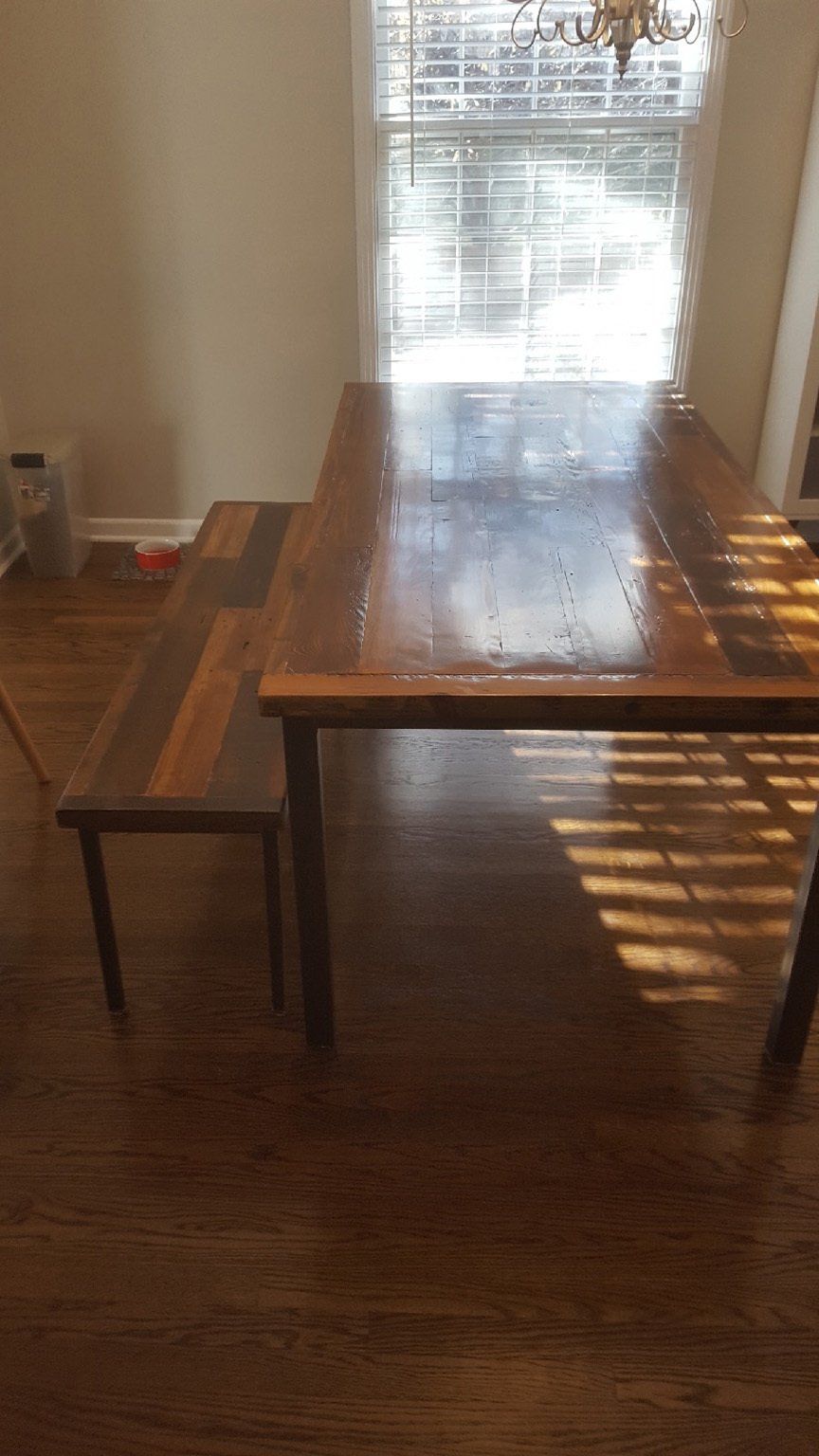 A wooden table and bench in a dining room next to a window.