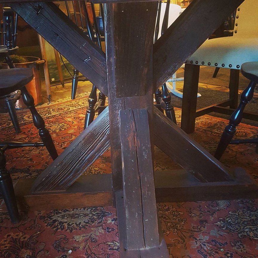 The base of a wooden table with a chair in the background