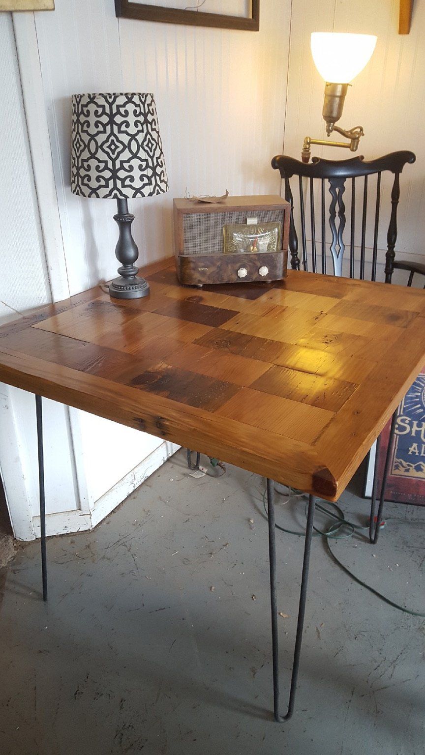 A wooden table with hairpin legs and a lamp on it in a room.
