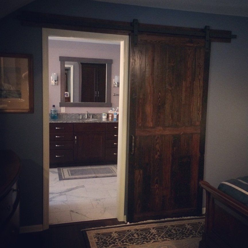 A bathroom with a sliding barn door leading to it