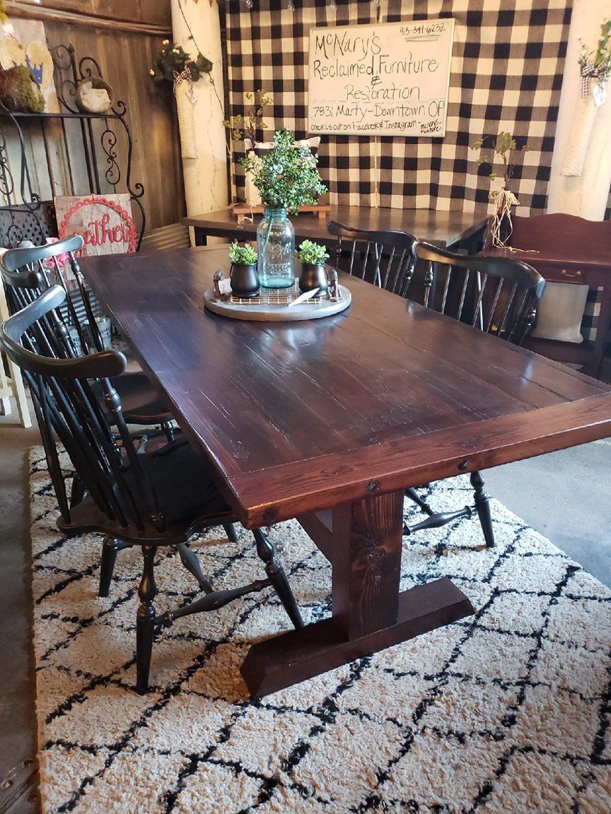 A wooden dining table with chairs and a rug in a room.