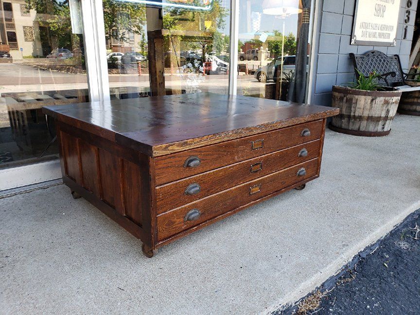 A wooden coffee table is sitting on the sidewalk in front of a store.