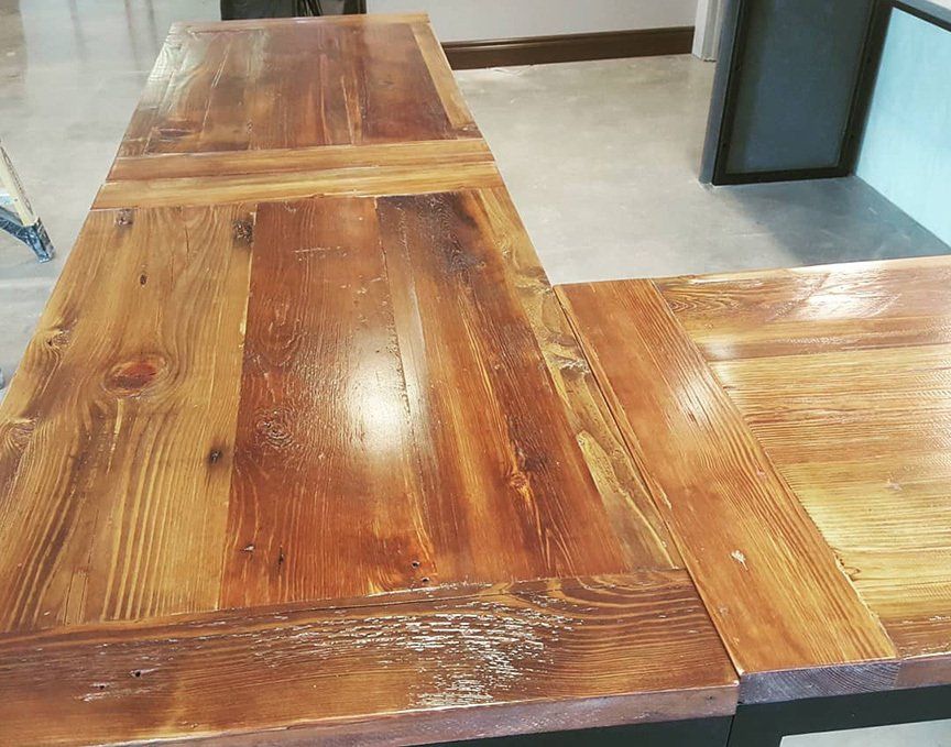 A wooden table with a metal frame is sitting on a concrete floor.