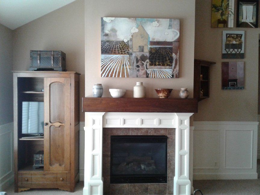 A living room with a fireplace and a painting on the wall above it