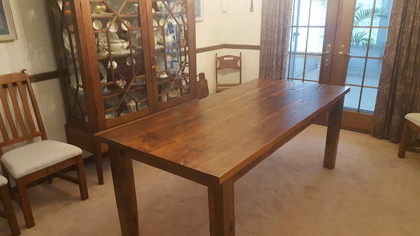 A wooden table is sitting in a dining room next to chairs.