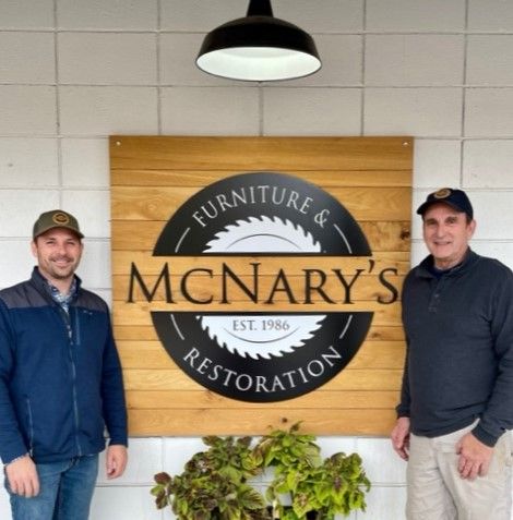 Two men standing in front of a sign for mcnary 's restoration