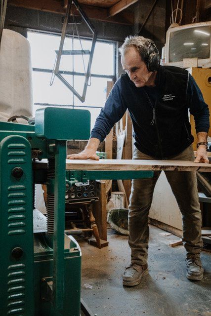 A man wearing headphones is standing next to a machine in a workshop.